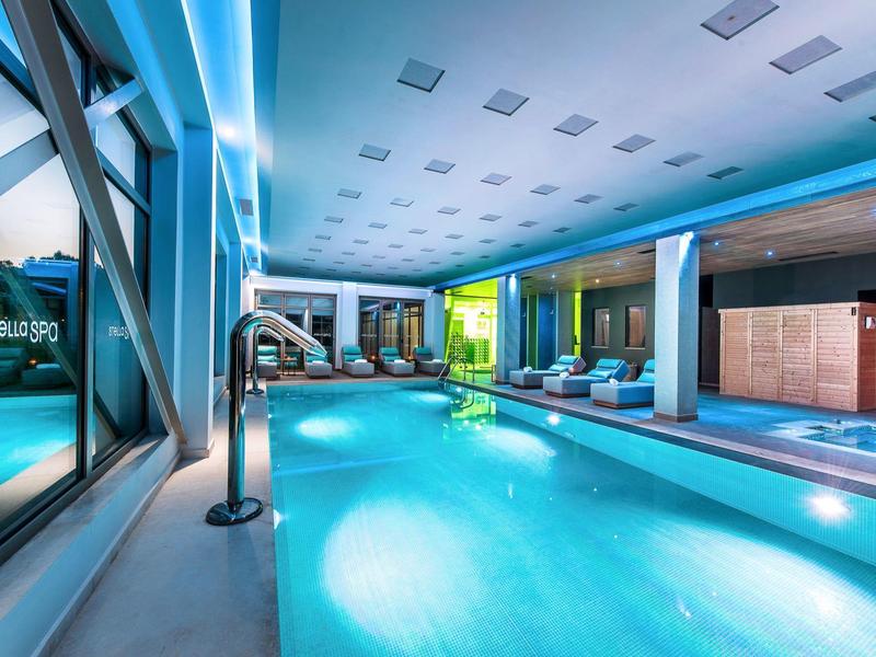 Moderner Innenpool mit Beleuchtung, Liegestühlen und glatten, hellen Wänden in kühlem Blau.