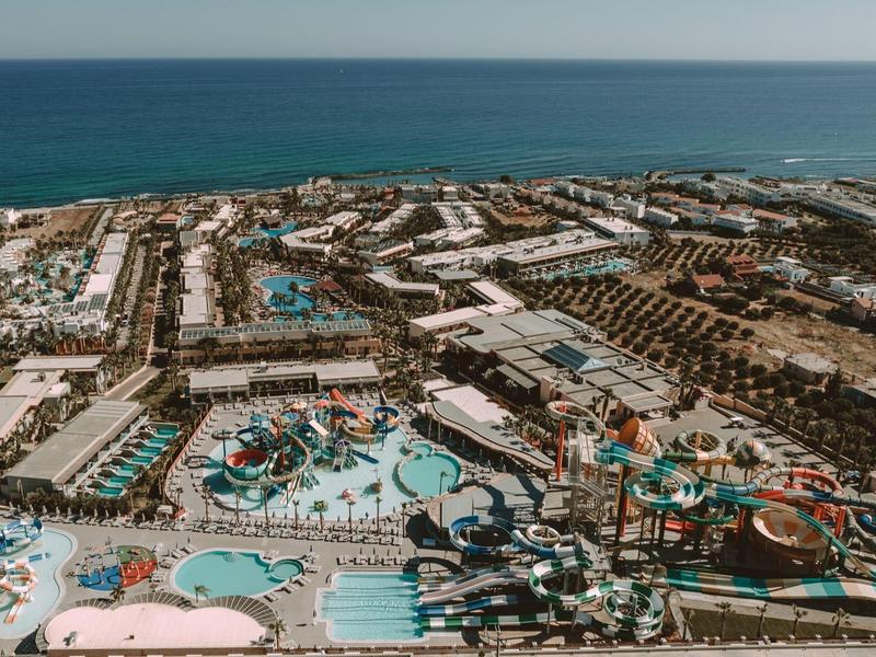 Luftaufnahme eines großen Wasserparks mit vielen Pools, Rutschen und angrenzendem Strand am Meer.