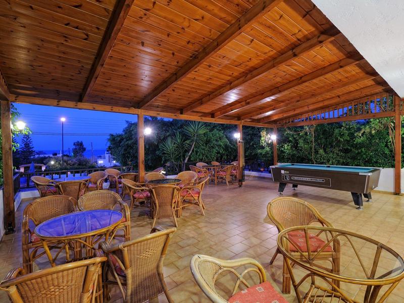 Zastřešená terasa s ratanovým nábytkem a kulečníkovým stolem, noční výhled na moře.