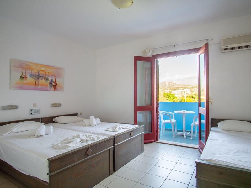 Světý hotelový pokoj s manželskou postelí, jednolůžkem a balkonem s výhledem na hory a moře.