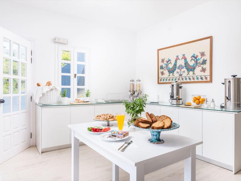 Lichte keuken met witte tafel, verse gebakjes en open raam met uitzicht op groen.