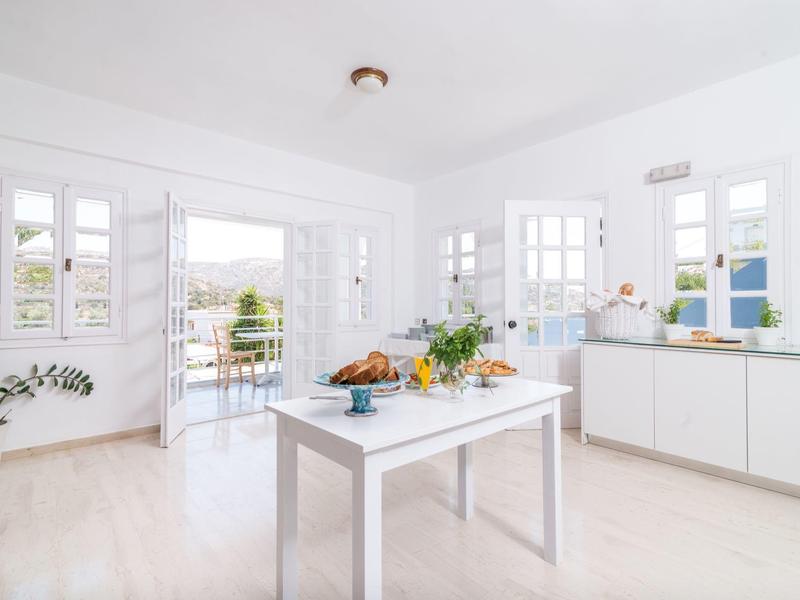 Lichte, moderne eetkamer met wit meubilair en uitzicht op terras en zee.