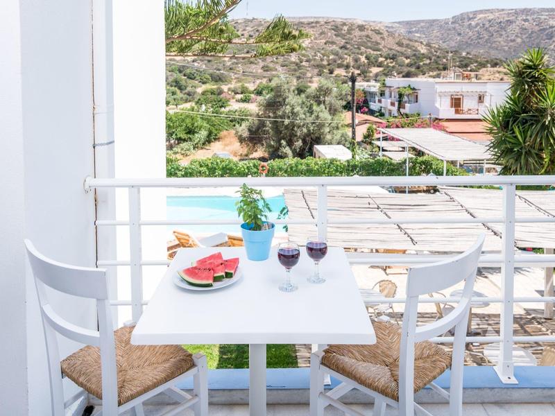 Balkontafel met drankjes en snacks, witte stoelen, uitzicht op de tuin en bergen.
