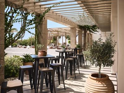Covered patio with tall tables and stools in a sunny outdoor area.