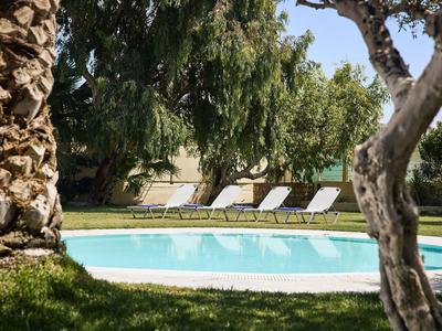 Round pool with white loungers in a shady garden area.