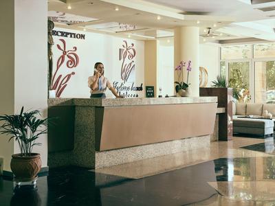 Jasna lobby hotelowa z recepcją, pracownikiem i poczekalnią z sofami.