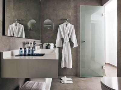 Nowoczesna łazienka z umywalką, ręcznikami, szlafrokiem i szklanymi drzwiami.