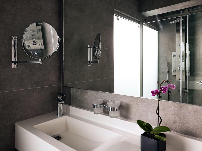 Nowoczesna łazienka z białą umywalką, lustrem i storczykiem na blacie.