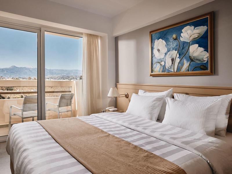 Nowoczesny pokój hotelowy z podwójnym łóżkiem, dużym oknem i widokiem na góry.