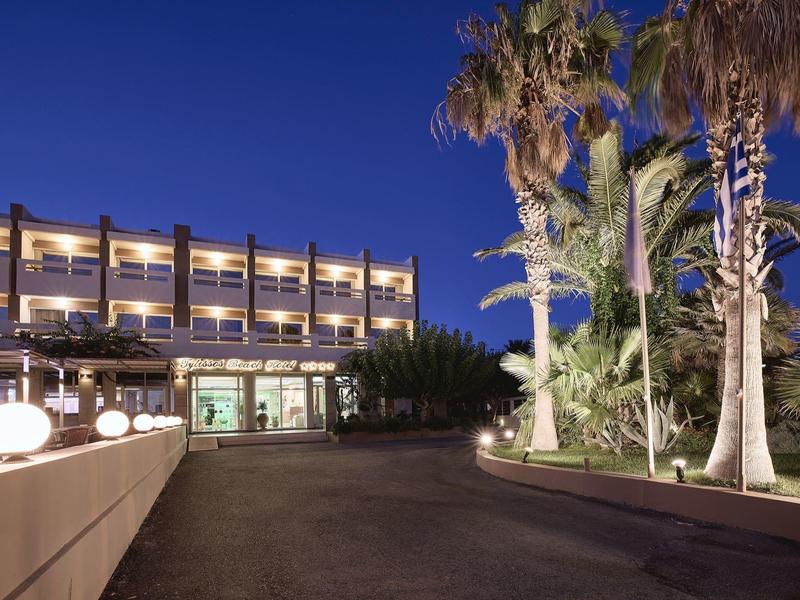 Nowoczesny budynek hotelu nocą z oświetlonymi palmami i czystym parkingiem.