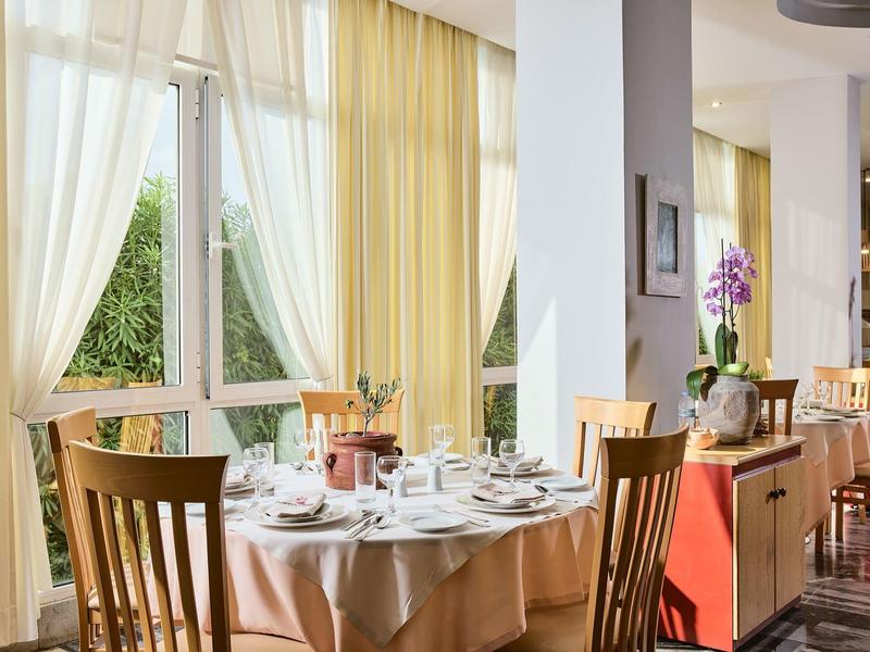 Jasna restauracja z nakrytym stołem i dużymi oknami z zasłonami.