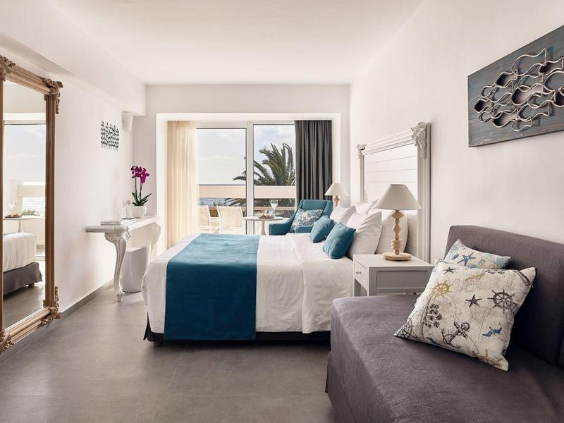 Nowoczesny pokój hotelowy z podwójnym łóżkiem, miejscem do siedzenia i widokiem na morze przez drzwi balkonowe