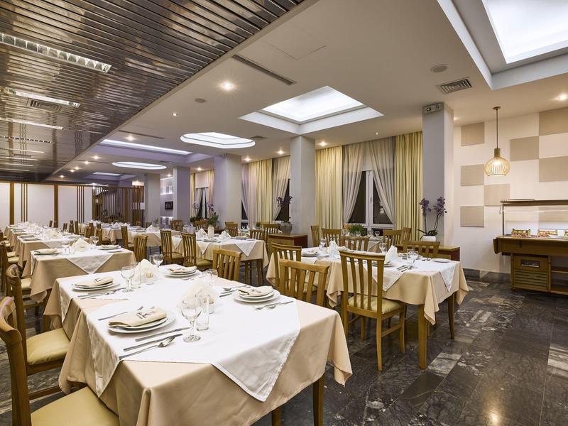 Elegancka jadalnia z nakrytymi stołami i ciepłym oświetleniem w hotelu.