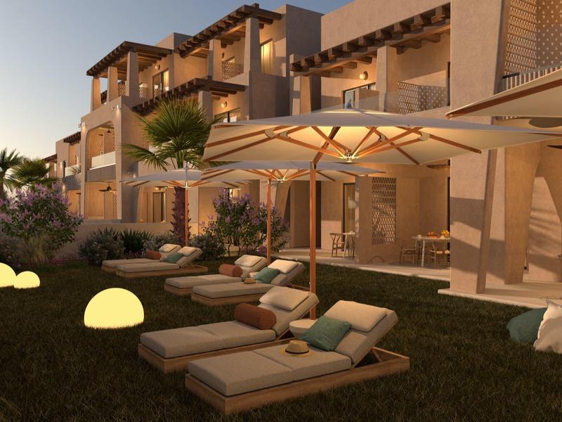 Avondexterieur van een modern hotel met ligstoelen en verlichte planten.