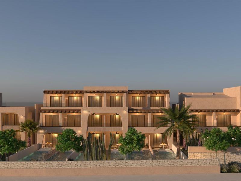 Modern hotelgebouw met verlichte balkons en palmbomen op de voorgrond bij schemering.