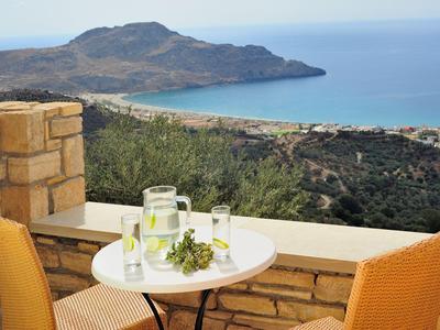 Terrasse avec table, deux chaises et vue sur la mer et les collines.