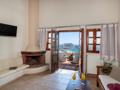 Area accogliente della camera d'hotel con camino, divani e vista su terrazza e mare.