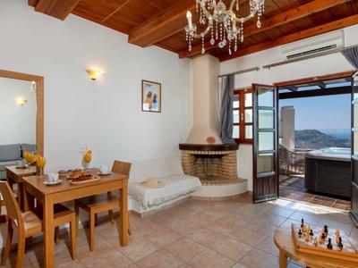 Soggiorno luminoso con soffitto in legno, tavolo da pranzo, camino e vista terrazza sul mare.