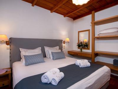 Camera d'hotel accogliente con letto matrimoniale, soffitto con travi in legno e cuscini decorativi.