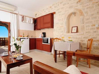 Cucina accogliente con pareti in pietra, mobili in legno e vista sul balcone e sul mare.