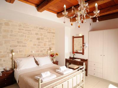 Camera d'hotel accogliente con letto matrimoniale, parete in pietra e soffitto con travi in legno.