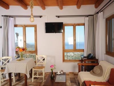 Accogliente zona camera d'hotel con tavolo da pranzo, divano e vista mare attraverso le finestre.