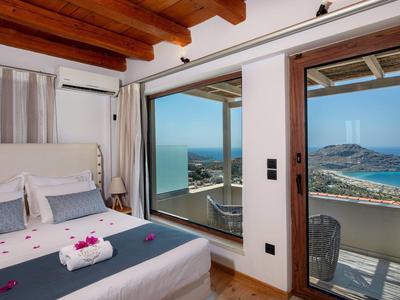 Camera lussuosa con letto matrimoniale e vista mare attraverso ampie finestre e balcone.