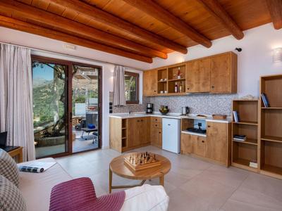 Cucina luminosa con mobili in legno, elettrodomestici moderni e accesso a una terrazza con vista sulle montagne.