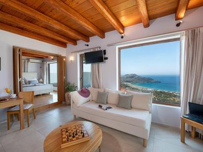 Soggiorno moderno con soffitto con travi in legno, divano bianco e grande finestra con vista mare.