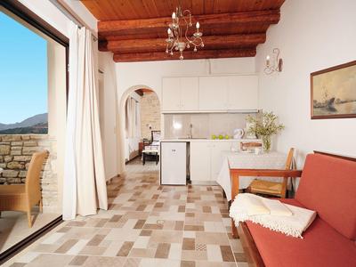 Stanza luminosa con divano, tavolo da pranzo, piccola cucina e accesso al balcone con vista.