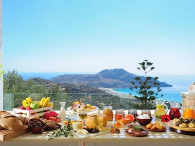 Un tavolo apparecchiato con vari cibi e bevande con vista sul mare sullo sfondo.