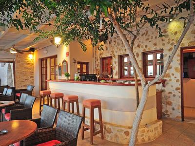 Bar confortable avec tabourets, tables et un arbre dans la cour d'un hôtel.