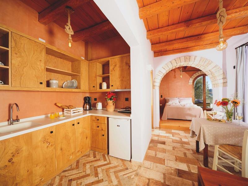 Cucina rustica dell'hotel con mobili in legno, tavolo da pranzo e vista sulla camera da letto.