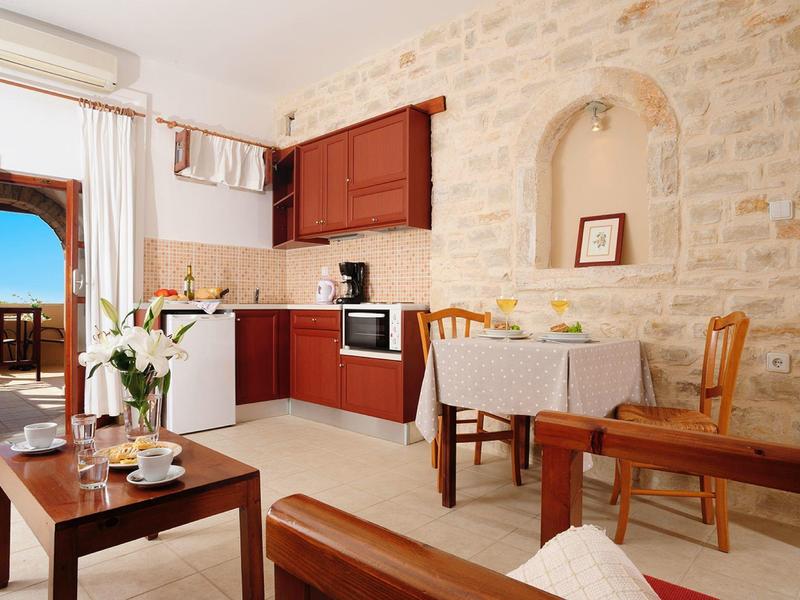 Cucina accogliente con pareti in pietra, mobili in legno e vista sul balcone e sul mare.