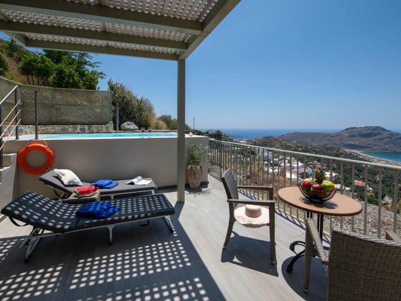 Balcone con lettini, tavolo e sedie con vista sul mare sotto un cielo azzurro