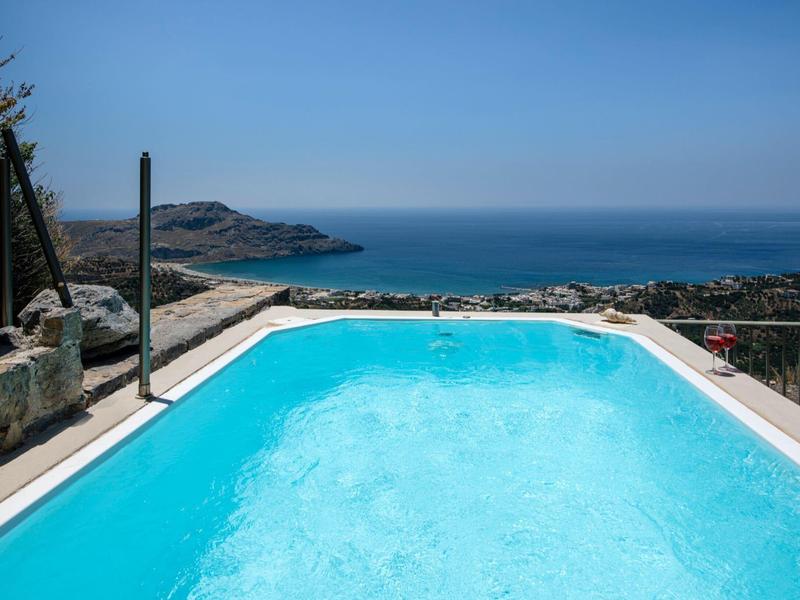 Piscina con vista sul mare e sul paesaggio costiero sotto un cielo limpido.