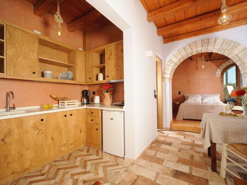 Accogliente angolo cucina con armadietti in legno, pavimento in marmo e vista sulla camera da letto.
