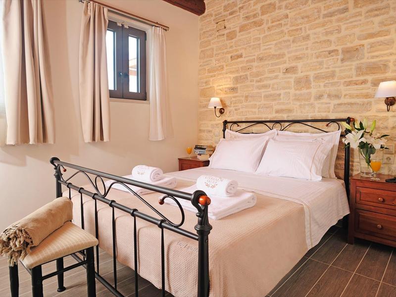 Camera accogliente con letto in ferro, pannelli di legno, comodini e luce calda.