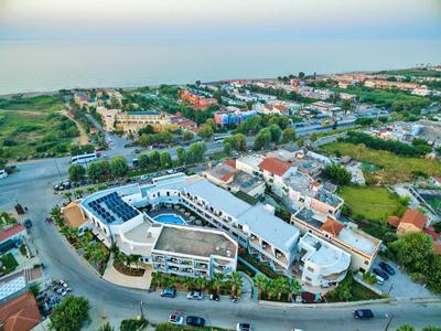 Luftaufnahme eines Wohnkomplexes mit weißen Gebäuden, roten Dächern und Solarpaneelen, umgeben von Grün.