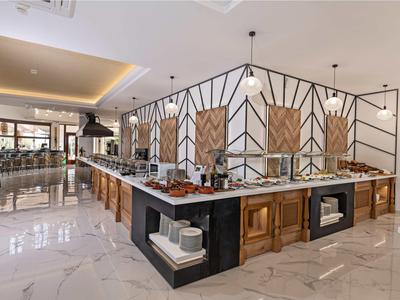 Nowocześnie zaprojektowany bufet hotelowy z drewnianymi ladami i marmurową podłogą.