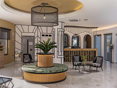 Hall d'hôtel moderne avec coin salon, plantes et éclairage élégant.