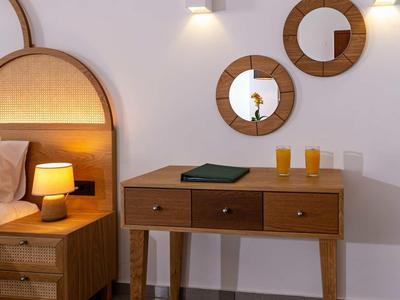 Jasny pokój z drewnianą komodą, okrągłymi lustrami i lampką nocną obok łóżka.