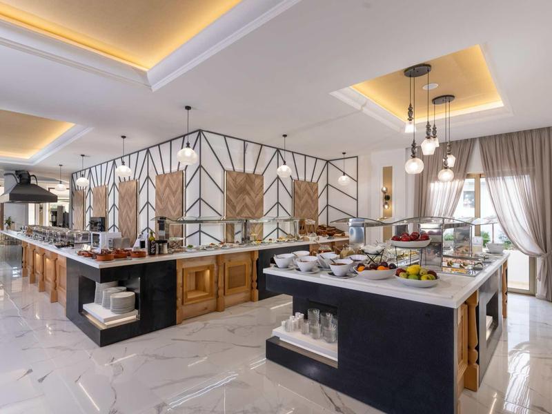 Moderner Buffetbereich mit Holz- und Marmorflächen, hellen Wänden und indirekter Deckenbeleuchtung.