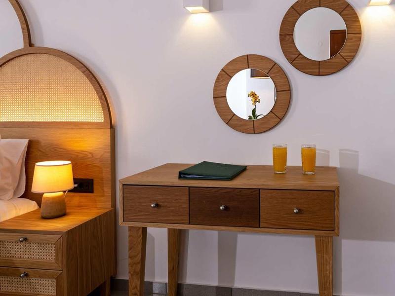 Helles Schlafzimmer mit Holzmöbeln, Nachttischlampe und drei runden Spiegeln an der Wand.