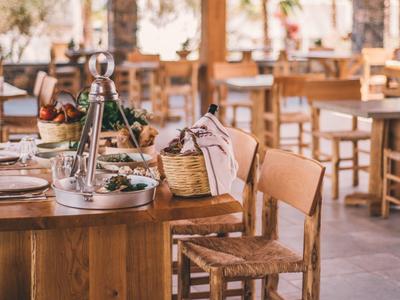 Restaurant rustique avec meubles en bois et tables dressées dans un cadre champêtre.