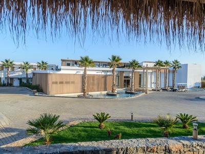 Edificio moderno di un hotel con palme e cielo azzurro limpido sullo sfondo.