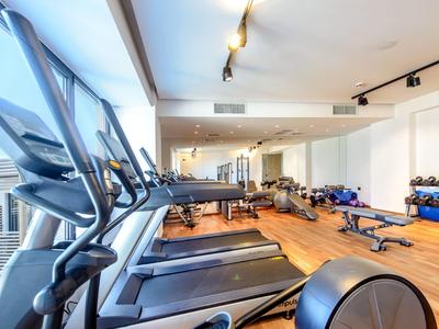 Palestra moderna con tapis roulant, manubri e parete a specchio in stanza luminosa