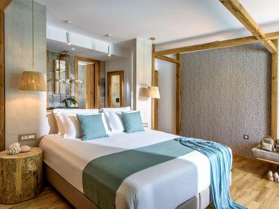 Camera d'hotel moderna con letto grande, dettagli in legno e arredamento elegante e tranquillo.