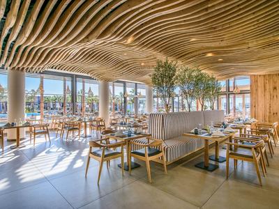 Ristorante luminoso e moderno con soffitto in legno e grandi finestre con vista sull'acqua.