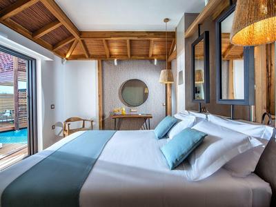 Chambre d'hôtel lumineuse avec lit double, bois apparents et accès à la piscine.